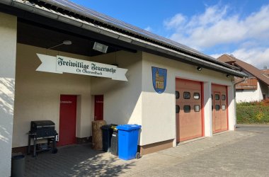 Blick auf das Feuerwehrhaus in Oberseelbach mit Eingangstür und großen roten Garagentoren