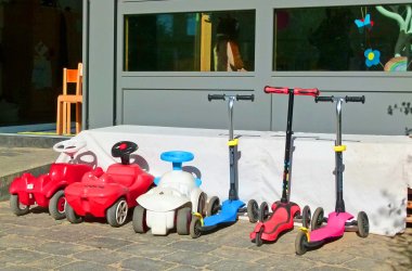 Mehrere Roller und Bobbycars, in einer Reihe aufgestellt