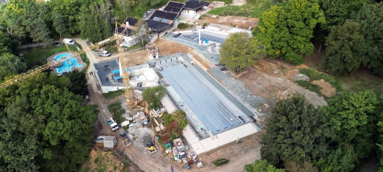 Drohnenaufnahme des Niedernhausener Schwimmbades aus der Luft, man sieht umfangreiche Bauarbeiten und Kräne um die leeren Schwimmbecken herum