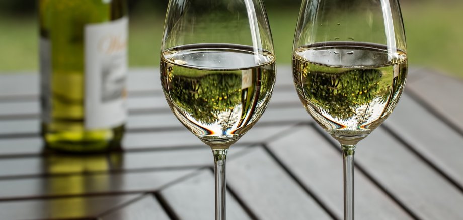 Zwei mit Weißwein gefüllte Gläser auf einem Holztisch