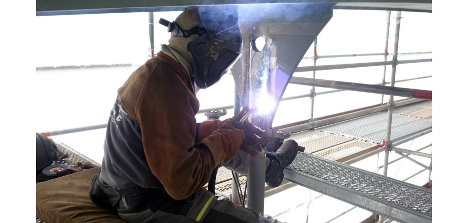 Ein Schweißer bei der Arbeit auf einem Gerüst