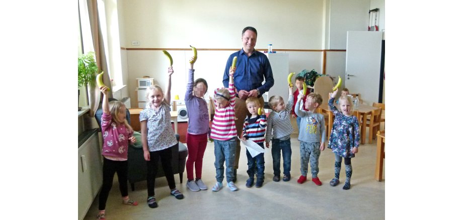 Eine Gruppe von Kindern und einem Erwachsenen, die Bananen hoch halten