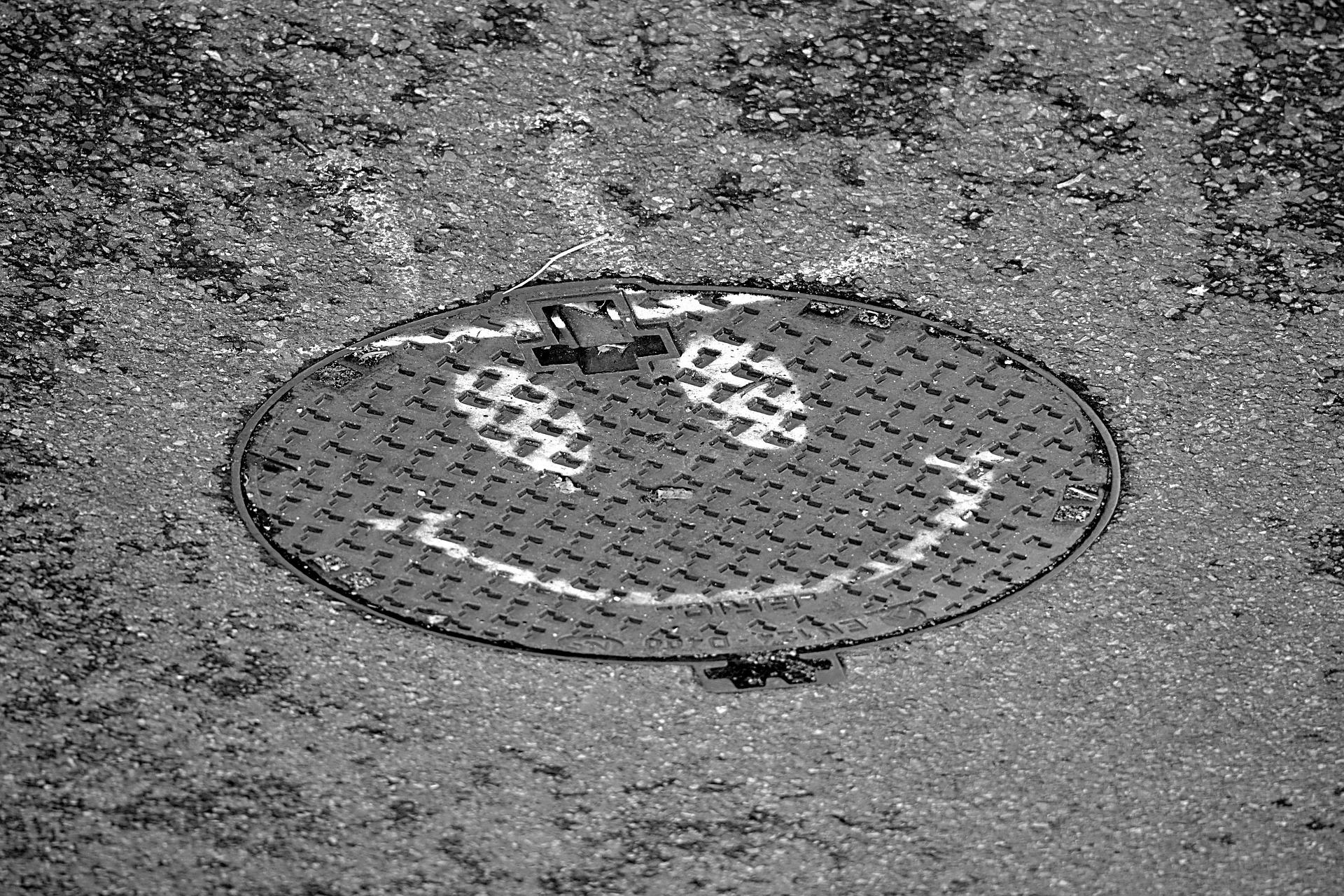 Gullideckel mit darauf gemaltem Smiley