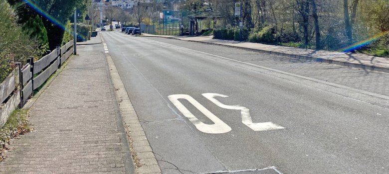 Eine bergab durch ein Wohngebiet führende Straße im Sonnenschein