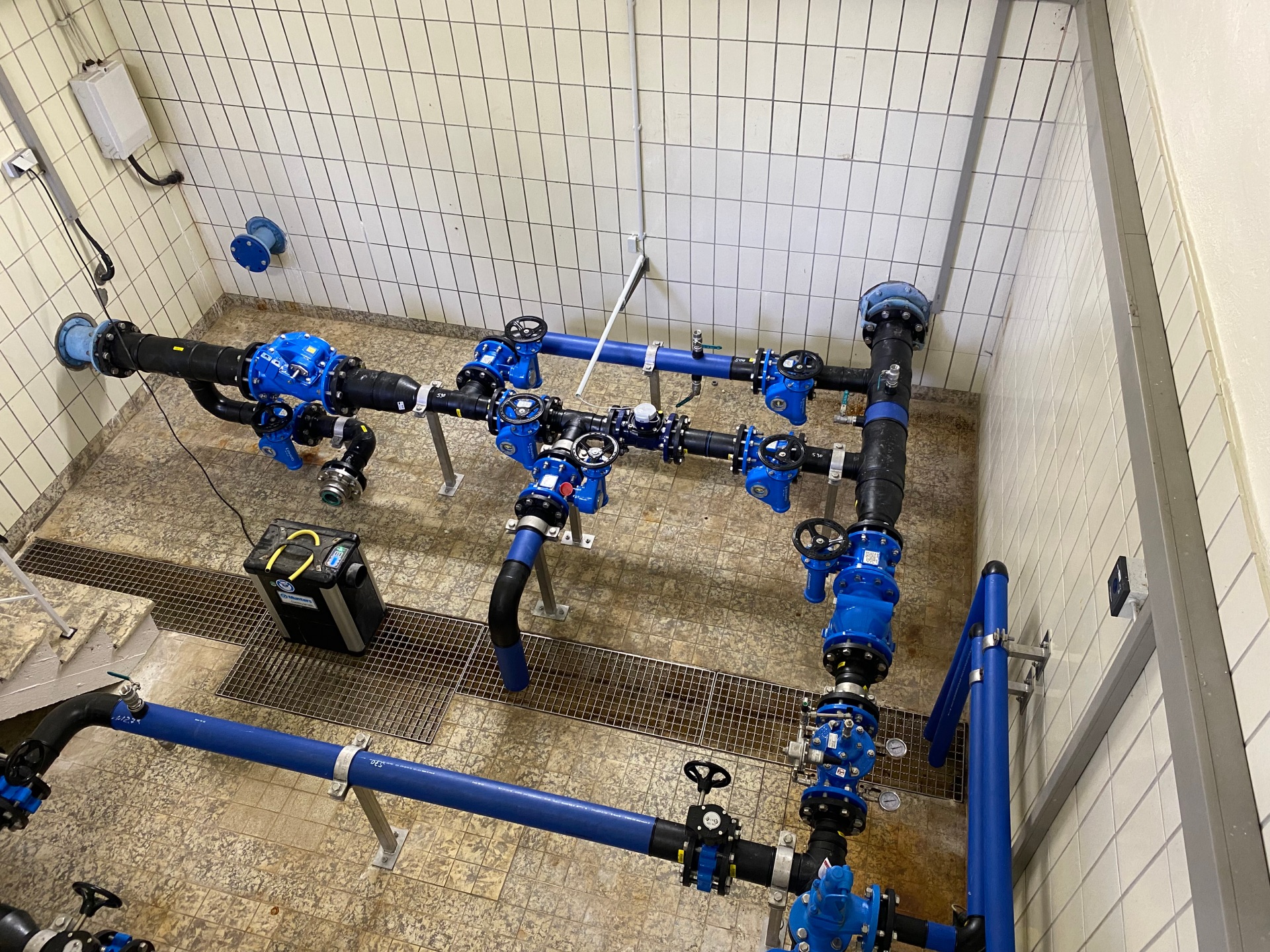 Blick in eine Aufbereitungsanlage für Trinkwasser: Durch einen hell gekachelten Raum verlaufen blaue Rohre