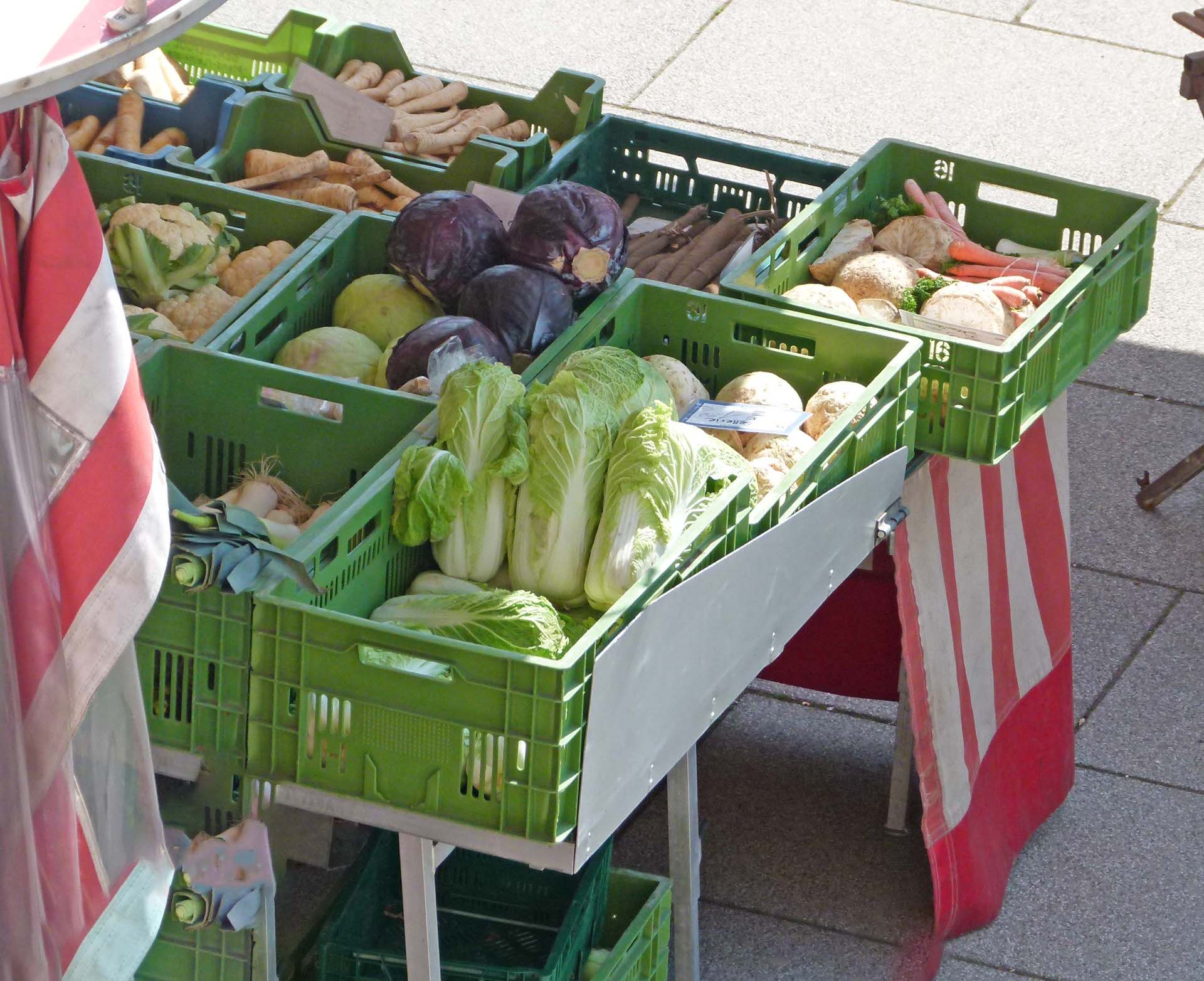 Blick von schräg oben auf einen Marktstand mit verschiedenen Gemüsesorten in der Auslage
