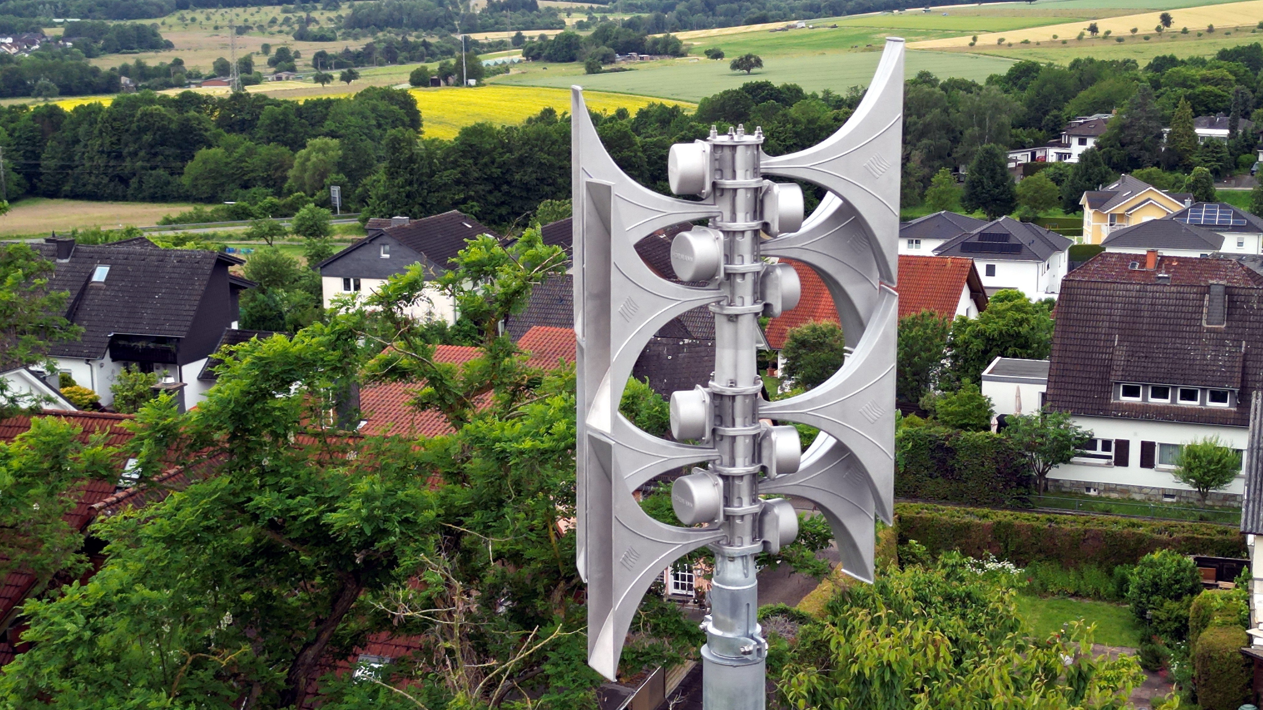 Eine Warnsirene mit Blick auf die Dächer eines Dorfes