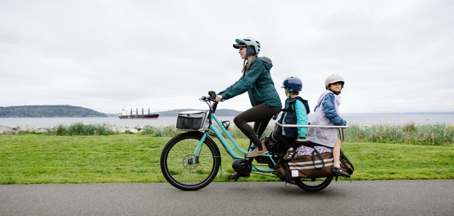 Eine Frau und zwei Kinder auf einem Lastenfahrrad